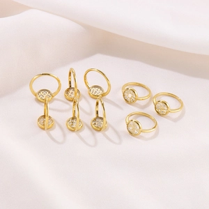 Collection of golden geometric zircon rings in wave and disk styles on silk background