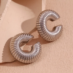 Detailed view of silver C-shaped chunky earrings with textured ribbed design on stone
