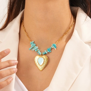 Gold paperclip chain necklace with blue stone beads and heart pendant on white suit