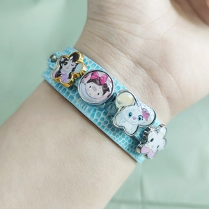 Close-up of sky blue faux leather bracelet with cartoon charms on a person's wrist