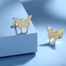 Detailed macro view of S925 sterling silver golden butterfly earrings with white crystals