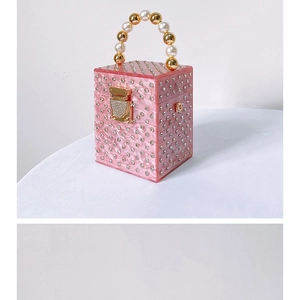 Macro detail of pink acrylic evening bag with faux pearl handle and crystal inlay