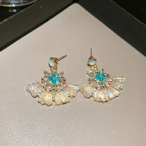 Macro shot of fan-shaped stud earrings with colorful pavé crystals on a jewelry tray