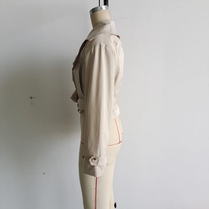 Vue détaillée des pattes de poignets et de la ceinture du trench-coat court beige