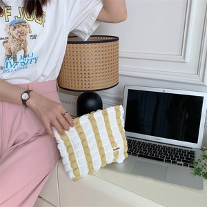Detail of yellow and white striped cloud makeup bag with woven texture held by model
