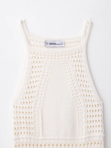 Close-up of white crochet knit halter dress showing intricate hollow texture and tag