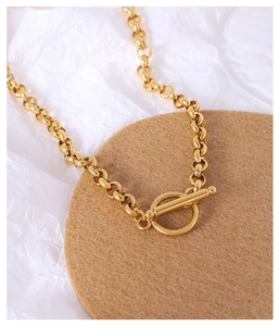 Close-up of golden chunky chain link necklace featuring a stylish OT buckle design