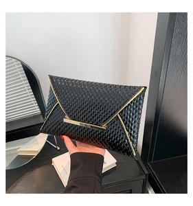 Dettaglio ravvicinato della pochette nera con stampa rettile e finiture in oro