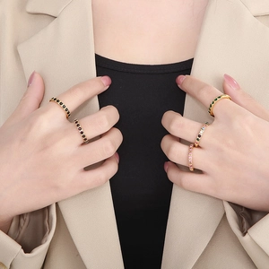 Detail of 3mm gold titanium rings with colorful zirconia worn on a beige blazer sleeve