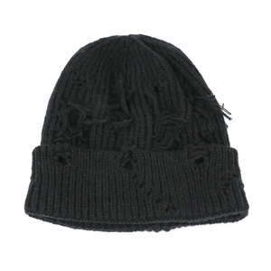 Close-up of distressed ripped details and raw fringe on black knit beanie hat