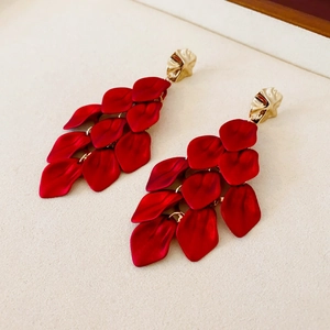 Macro shot of layered red petal tassel earrings with golden geometric stud accents