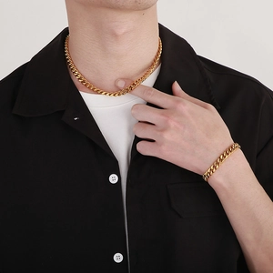 Polished golden Cuban link necklace and bracelet set worn by male model on black shirt