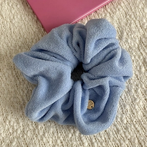Close-up of light blue towel fabric headband with soft texture and golden metal tag