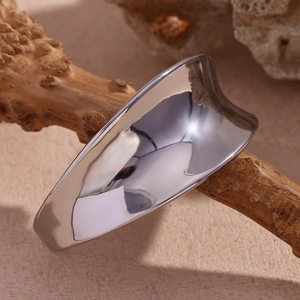 Macro view of wide silver liquid-style irregular concave metal ring on a branch