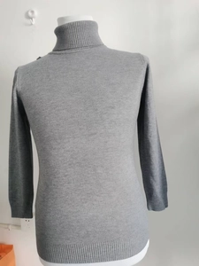 Detailed close-up of grey high-neck sweater fabric texture and ribbed collar design