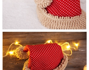Detailed view of a plush red Christmas hat with white cross pattern and warm LED string lights