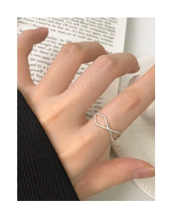 Detail of S925 silver infinity ring with twist rope texture on a hand with book background