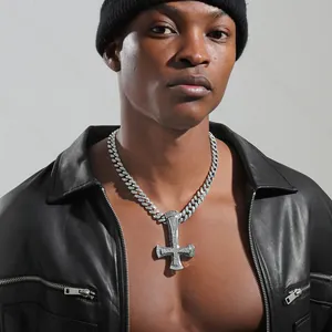 Close-up of iced out inverted cross pendant with silver cuban chain on male model