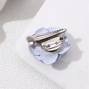 Detail view of the light blue denim camellia brooch with metal hair clip and pin backing
