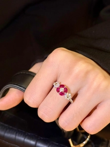 Detailed view of flower-shaped ring with red zircons and silver band on a hand