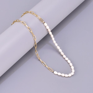 Detailed view of gold paperclip chain and baroque pearls on a minimalist display stand