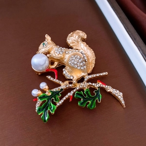 Détail d'une broche écureuil vintage avec perles et émail vert sur une branche