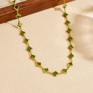 Elegant gold plated stainless steel necklace with square green gemstone on beige texture