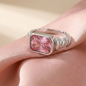Macro view of a silver twisted rope ring featuring a large emerald-cut pink gemstone
