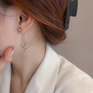 Close-up of silver beaded tassel earrings with cascading chains on a model