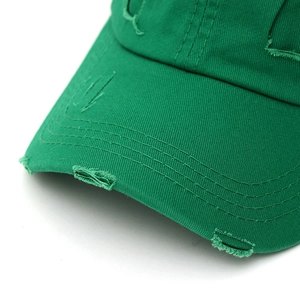 Close-up of emerald green cotton baseball cap featuring distressed torn edges and double stitching
