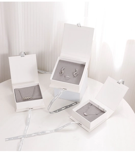 Detail of white jewelry gift boxes for necklace and rings with grey velvet lining and ribbon