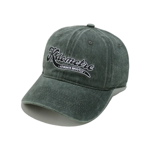 Close-up of white 3D Kilometre embroidery on a dark gray washed cotton baseball cap