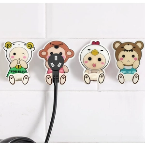 Set of four cute animal-shaped wall hooks holding a power plug on white tiles