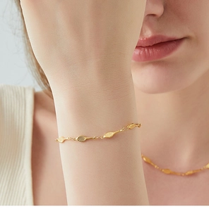 Close-up of gold tennis racket charm bracelet and necklace set on model's wrist and neck