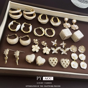 Elegant gold plated floral and heart pearl earrings displayed on a brown jewelry tray