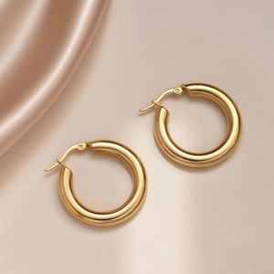 Detailed macro view of polished gold round earrings with latch-back closure on silk