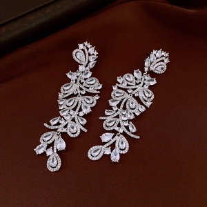 Detailed macro shot of vintage silver flower earrings with crystals on dark fabric