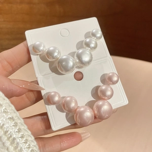 Detailed close-up of gradient pearl stud earrings in white and pink tones for women