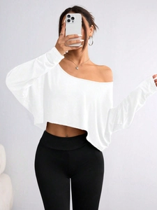 Detail of white off-shoulder long sleeve crop top in textured knit fabric on model