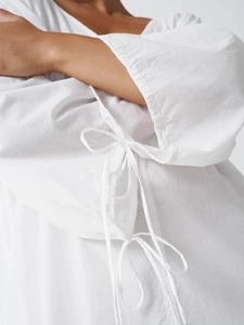 Detail of white cotton dress showing lace-up drawstring cuffs and textured fabric