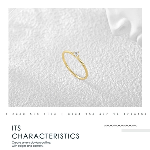 Detail view of gold minimalist four-prong solitaire ring on elegant white textured surface