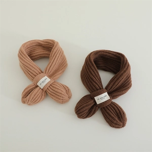 Detail of cross-knot knitted winter scarves in camel and dark coffee brown colors