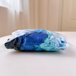 Detail of satin scrunchies in gradient blue shades neatly organized in clear packaging