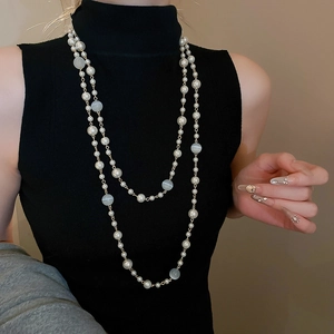 Détail d'un collier multicouche avec perles et pierres œil de chat sur col roulé