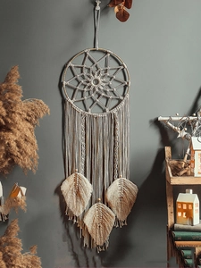 Detail of bohemian woven macrame dreamcatcher with cotton feathers and wood beads