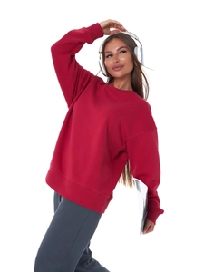 Detail of red crewneck sweatshirt featuring thick knit fabric and ribbed cuffs on model