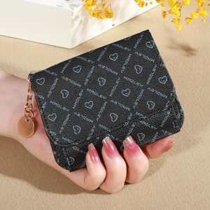 Close-up of hand holding a black textured wallet with blue heart and letter patterns