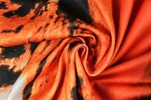 Macro shot of smooth orange and black tiger print fabric with elegant spiral draping