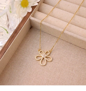 Detailed macro view of a gold flower pendant necklace with pavé zircon stones