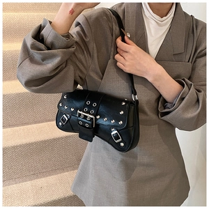 Detail of black punk shoulder bag with silver rivets and buckles on model